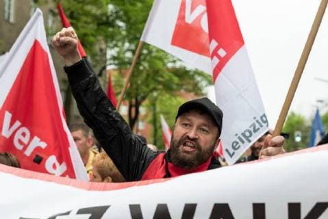 Deutschland, Berlin - 24.04.2018 Ein Demonstrant h??lt die Faust in die Luft w??hrend der Demonstration gegen die Verleihung des Axel Springer Award 2018 an Amazon-Gr??nder Jeff Bezos f??r sein vision??res Unternehmertum . Mitarbeiter des Unternehmens demonstrierten unter dem Motto Make Amazon Pay again gegen den Axel Springer Award den nach Angaben des Medienunternehmens herausragende Pers??nlichkeiten, die in besonderer Weise innovativ sind, M??rkte schaffen und ver??ndern und sich ihrer gesellschaftlichen Verantwortung stellen erhalten. Gewerkschaften kritisieren die schlechten Arbeitsbedingungen in Amazons Logistik-Zentren die sie f??r nicht preisw??rdig erachten. Germany, Berlin - 24.04.2018 A protester holds his fist in the air during the demonstration against the awarding of the Axel Springer Award 2018 to Amazon founder Jeff