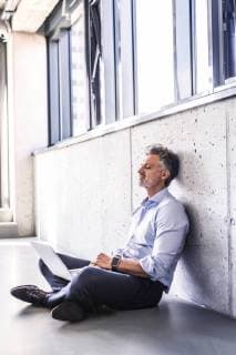 Mature businessman with laptop sitting on the floor leaning against the wall model released Symbolfoto property released  HAPF02697