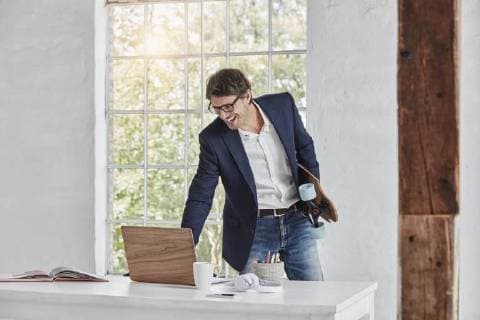 Laughing businessman with skateboard using laptop on desk model released Symbolfoto property released  RORF01144