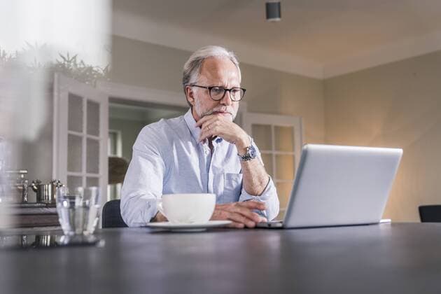 Portrait of mature man sitting at table using laptop at home model released Symbolfoto property released  UUF12921