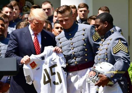 President Donald Trump receives a jersey from Army Black Nights team captains John Voit (C) and Ahmad Bradshaw (R) at a ceremony where Trump presented the Commander-in-Chief?s Trophy to the U.S. Military Academy football team, in the Rose Garden at the White House in Washington, D.C. on May 1, 2018. The Commander-in-Chief Trophy is presented each year to the season s winner of the American college football competition among the three service academies.  WAP20180501306 KEVINxDIETSCH