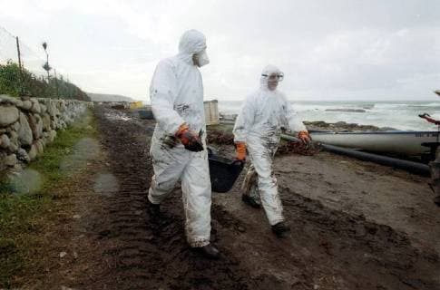 Volunteers of the Spanish environmental organization Tragsa clean on Thursday 12 12 2002 a stretch of coast at Mougas Galicia contaminated by the oil of the sunken tanker Prestige For cleaning they have only the simplest means available. There are no devices everywhere to clean the beaches of the oil Government around Prime Minister José Maria Aznar increasingly under pressure