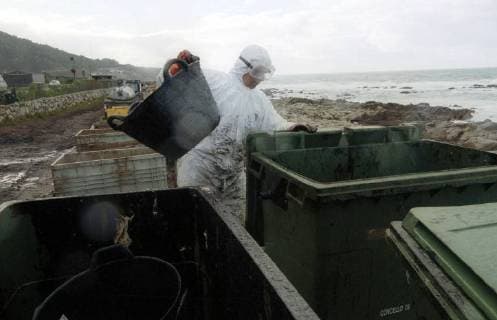 Volunteers of the Spanish environmental organization Tragsa clean on Thursday 12 12 2002 a stretch of coast at Mougas Galicia contaminated by the oil of the sunken tanker Prestige For cleaning they have only the simplest means available There are missing everywhere devices to clean the beaches of the oil Therefore, the Government around Prime Minister José Maria Aznar increasingly under pressure