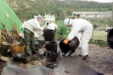 Volunteers of the Spanish environmental organization Tragsa clean on Friday 13 12 2002 a stretch of coast at Mougas Galicia contaminated by the oil of the sunken tanker Prestige For cleaning they have only the simplest means available There are missing everywhere devices to clean the beaches of the oil From the tanker is still running out of oil