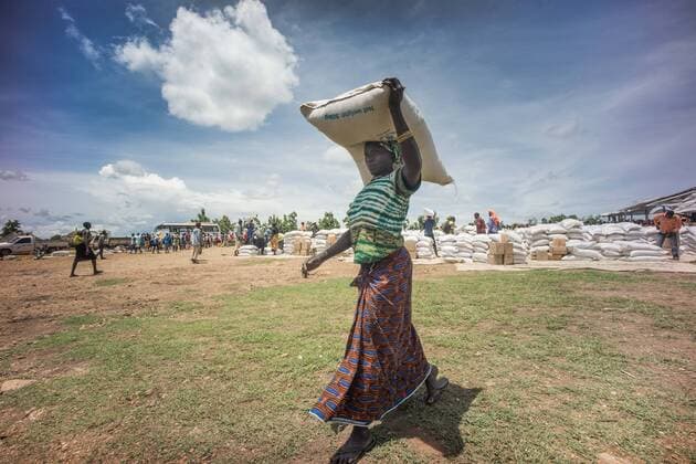 May 7, 2018 - Bidi Bidi, Uganda - A female South Sudanese refugees seen carrying a pack of 50 KG of cassava flour on top of the her head..The Bidi Bidi refugee settlement in northern Uganda near the South Sudanese border is currently the largest refugee camp in the world, hosting over 250,000 South Sudanese refugees fleeing the conflict. The world food program is providing monthly basic food supply for the refugees in the settlement. Bidi Bidi Uganda - ZUMAs197 20180507_zab_s197_010 Copyright: xGeovienxSox