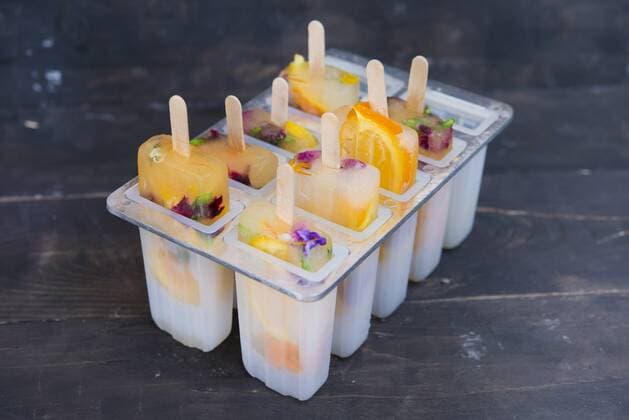 Homemade orange and lemon popsicles with edible flowers  SKCF00442