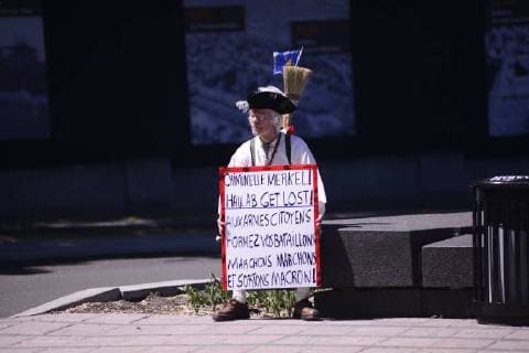 June 9, 2018 - Quebec City, Ontario, Canada - A lonely aged protester sitting with a sign denouncing Angela Merkel during a rally to protest the G7 summit in Quebec City, Canada on 9 June 2018. During the last day of the G7 summit that is happening in La Malbaie, Quebec, protesters came on to the streets to protest the summit in Quebec City. Quebec City Canada  - ZUMAn230 20180609_zaa_n230_1050 Copyright: xArindamxShivaanix