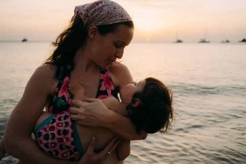 Mother holding little daughter on her arms in front of the sea by sunset model released Symbolfoto  GEMF01979