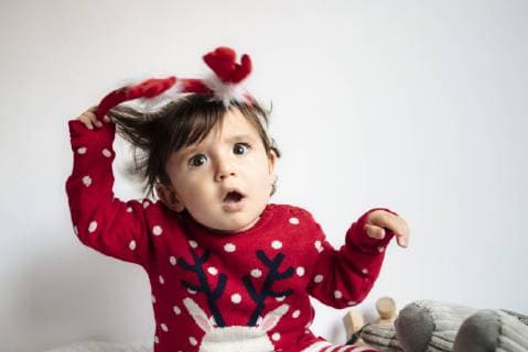 Portrait of disgusted baby girl pulling off reindeer antlers headband model released Symbolfoto  GEMF01943