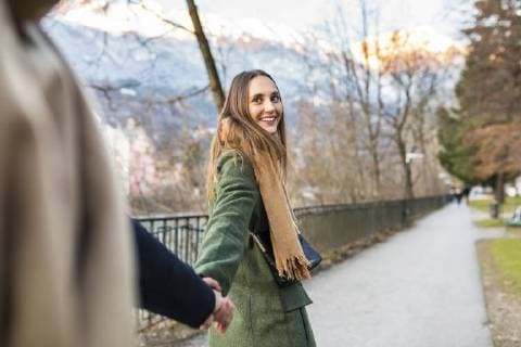 IMAGO Creative: Countdown bis Weihnachten, Nach Hause reisen Austria, Innsbruck, portrait of happy young woman strolling hand in hand with her boyfriend at winter time model released Symbolfoto  WPEF00231