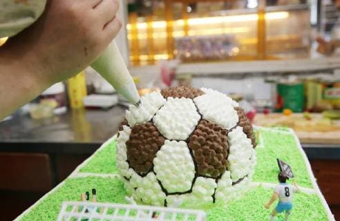 China: Football shaped cake Bakers make a World Cup themed cake at a bakery in Nantong, east China s Jiangsu Province. People can see football and football field at the cake. CHINA OUT Nantong Nantong China  XuxCongjun