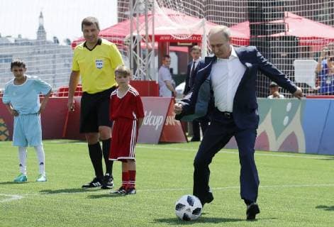MOSCOW, RUSSIA - JUNE 28, 2018: Russia s President Vladimir Putin (R) kicks the ball as he visits the 2018 FIFA World Cup Football Park in Red Square. Mikhail Metzel TASS  TS086D63