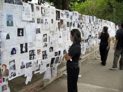 BRU98 - - PHUKET, THAILAND : A woman looks at a wall with pictures of missing people near the city hall of Phuket, Thailand, Saturday 01 January, after the region was hit by Tsunami waves on 26 December. The Tsunami wave killed last Sunday more than 120,000 people across South and Southeast Asia. GERARDxGAUDIN  x2494176x