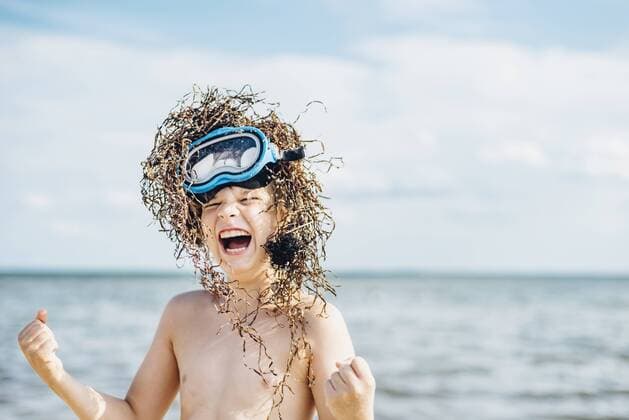 Carefree boy wearing seaweed wig on the beach model released Symbolfoto  MJF02294