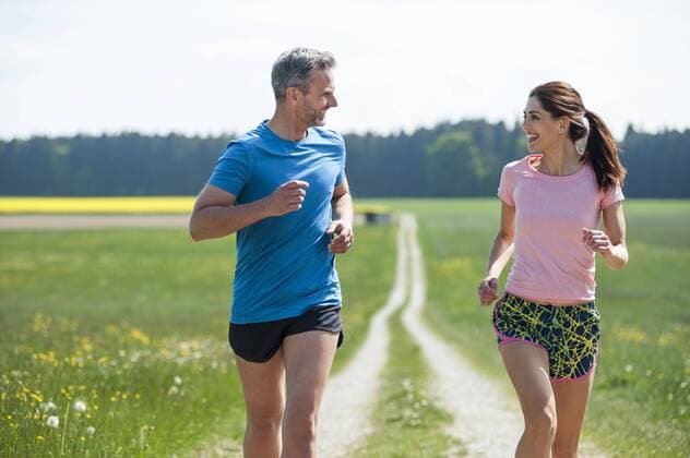 Couple running on field path model released Symbolfoto  DIGF04349