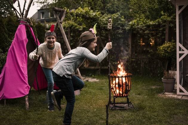 IMAGO Creative: Digitale Welt, Verzicht auf Technologie Two girls wearing feather headdress, dancing with twist bread around the camp fire model released Symbolfoto property released  MOEF01214