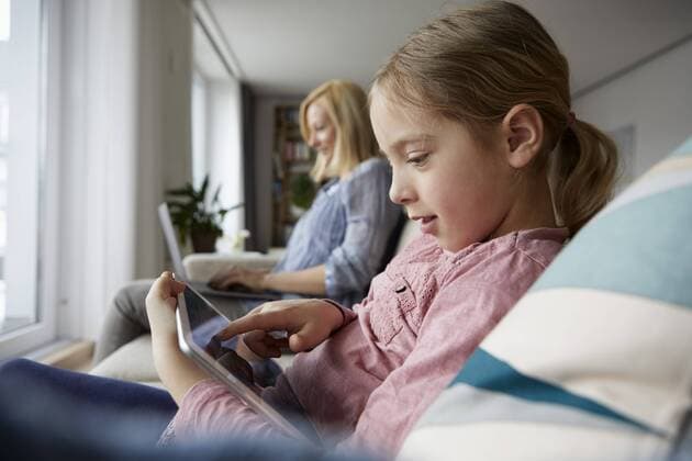 Mother and daughter at home sitting on couch using laptop and tablet model released Symbolfoto property released  RBF06298