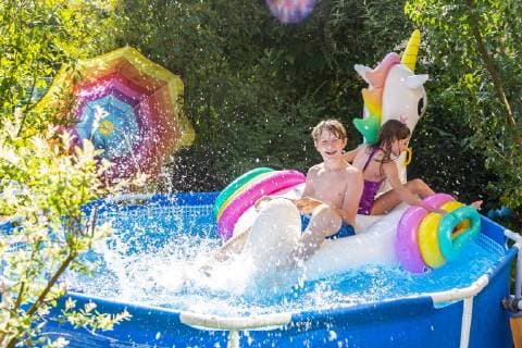 Brother and sister with oversized unicorn swim toy in paddling pool model released Symbolfoto  SARF03778