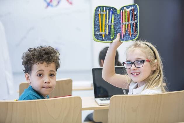 Portrait of schoolboy and schoolgirl with laptop and pencil case in class model released Symbolfoto property released  WESTF24227