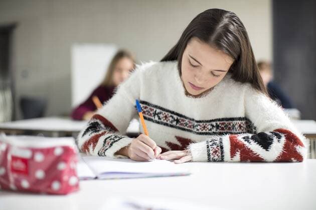 Teenage girl writing in exercise book in class model released Symbolfoto property released  ZEF15657
