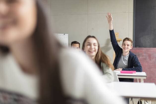 Smiling teenage boy raising hand in class model released Symbolfoto property released  ZEF15661