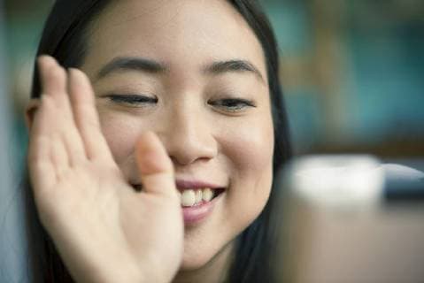 Young woman waving at camera while video conferencing on digital tablet  Copyright: FrédéricxCirou B59880625