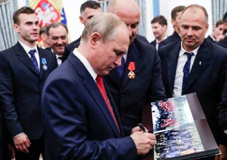 MOSCOW, RUSSIA - JULY 28, 2018: The President of Russia Vladimir Putin (C) signs an autograph as he looks at photographs after a ceremony to present government awards to Russia s national men s football team and coaches at the Kremlin; the Russian national team reached the quarterfinals at the 2018 FIFA World Cup. Mikhail Metzel TASS  TS08B0C5
