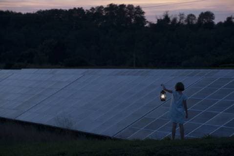 IMAGO Creative: Landleben, Mit Nachhaltigkeit grün auf dem Land leben Girl standing in front of solar panels at twilight with old-fashioned lantern in hand  Copyright: OdilonxDimier B18961525