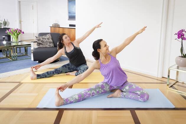 An image of two women doing yoga in the living room at home  1032100210