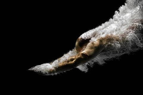 An image of a diving man in a black pool *** An image of a man diving in a black pool  1032100818
