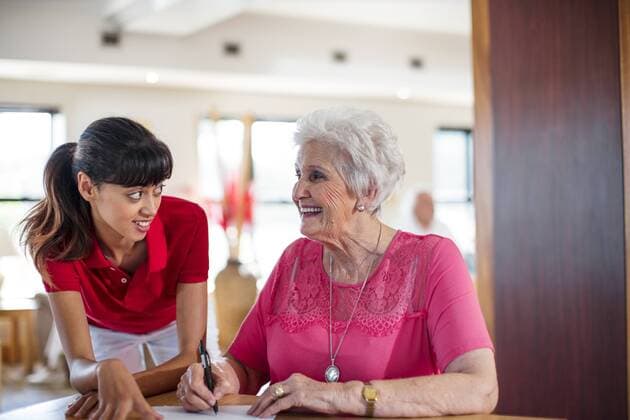 Senior woman signing a contract, nurse helping her model released Symbolfoto property released  ZEF14241