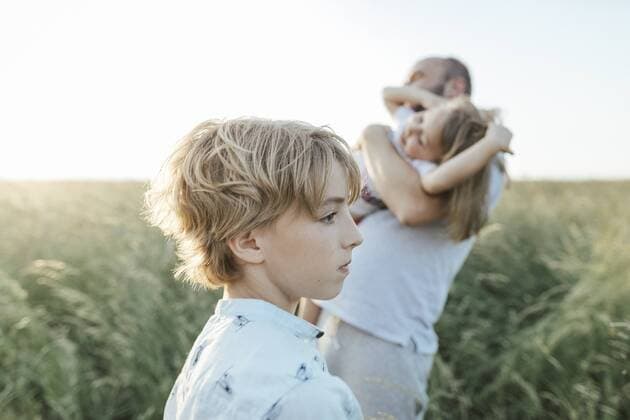 Sad boy with father and sister playing together in the background model released Symbolfoto  KMKF00373
