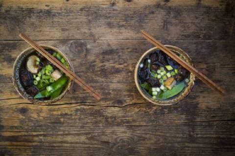 Two bowls of Japanese miso soup with sugar peas, shitake mushrooms, tofu and mung sprouts  LVF07275