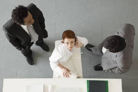 Businesswoman making phone call with colleagues standing nearby  Copyright: FrédéricxCirou B50394606