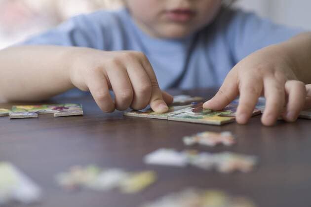 A young boy doing a jigsaw puzzle, focus on hands  Copyright: VladimirxGodnik fStopImages1046010