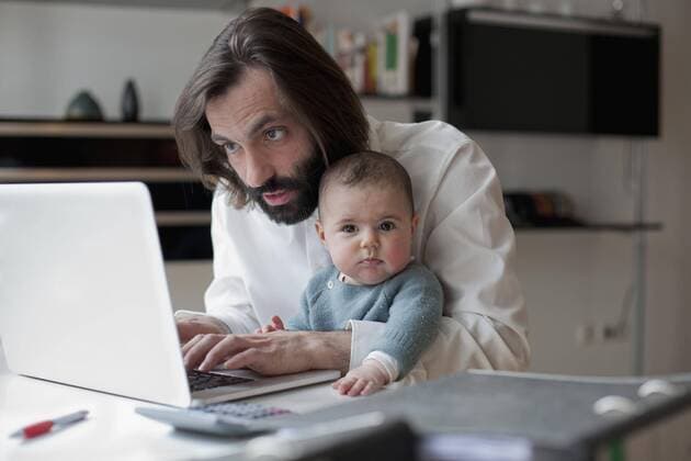 Man working on laptop while sitting with baby girl at home  Copyright: Antenna fStopImages1331040