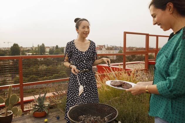 Smiling woman serving freshly grilled steak to female friend on patio  Copyright: LarryxWashburn fStopImages1687031