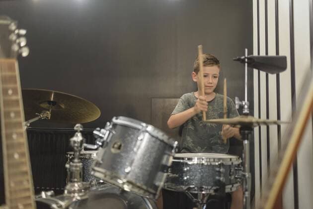 Boy playing drum against wall at home  Copyright: VladimirxGodnik fStopImages1706020
