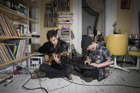 Two young men playing instruments in their living room New York City, New York, USA  Copyright: Antenna fStopImages815019