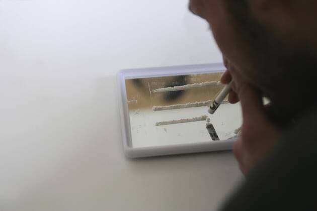 Man holding rolled bank note over lines of cocaine  Copyright: Halfdark fStopImages089034