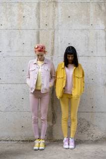 Two alternative friends having fun, wearing yellow and pink jeans clothes, looking down model released Symbolfoto  AFVF01043