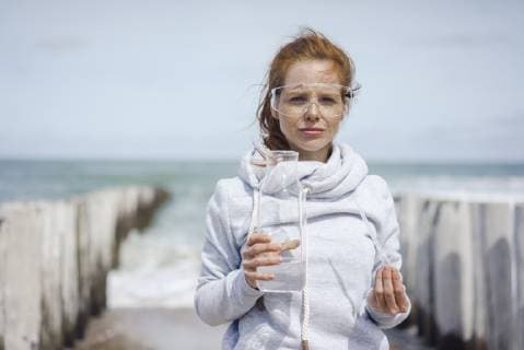 IMAGO Creative: Corporate: Klimaschutz, Digitalisierung und Urbanisierung IMAGO Creative: Klimawandel - Zukunft und Innovation Scientist with safety glasses taking water samples at the beach model released Symbolfoto  KNSF04300