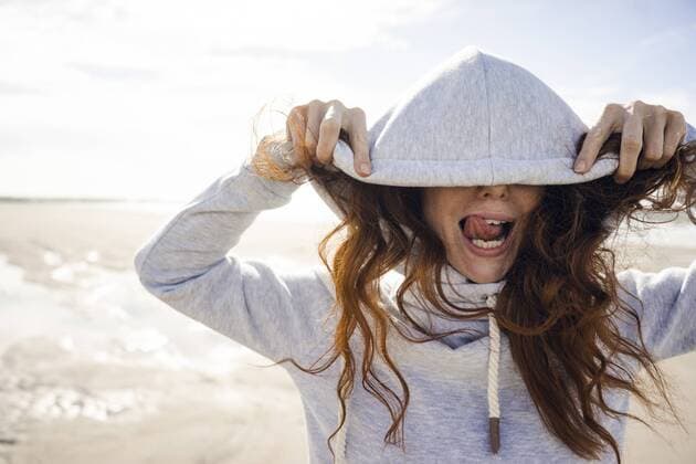 Woman having fun on a windy beach, wearing hood model released Symbolfoto  KNSF04232