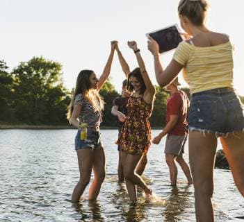 Group of happy friends with tablet in a river at sunset model released Symbolfoto  UUF14822