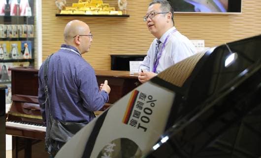 (181010) -- SHANGHAI, Oct. 10, 2018 -- An exhibitor (R) talks with a visitor by a piano during the Music China held in east China s Shanghai, Oct. 10, 2018. The 2018 Music China, a musical instrument trade show, opened on Wednesday in Shanghai. Over 2,200 musical instrument companies and dealers from 31 countries and regions participate in the show. ) (sxk) CHINA-SHANGHAI-MUSIC CHINA (CN) FangxZhe 