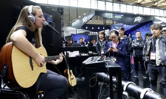 (181010) -- SHANGHAI, Oct. 10, 2018 -- A performer sings while playing the guitar during the Music China held in east China s Shanghai, Oct. 10, 2018. The 2018 Music China, a musical instrument trade show, opened on Wednesday in Shanghai. Over 2,200 musical instrument companies and dealers from 31 countries and regions participate in the show. ) (sxk) CHINA-SHANGHAI-MUSIC CHINA (CN) FangxZhe 