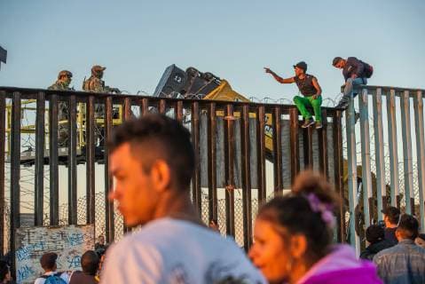 Nov 14, 2018 - Tijuana, Mexico - Asylum seekers from Central America, aka the Migrant Caravan , converse with US Border Patrol atop the border fence the US Mexico border in Tijuana. The forklifts were there to modify the border fence to add more concertina wire atop the fence. Tijuana Mexico - ZUMAs157 20181114_tim_s157_016 Copyright: xVitoxDixStefanox