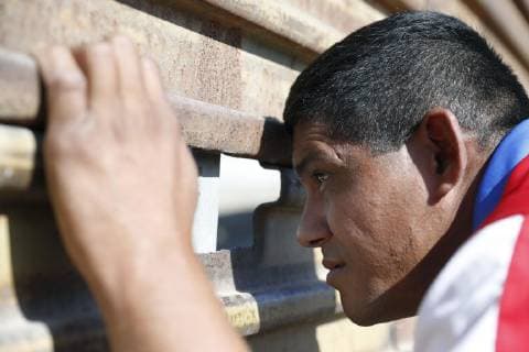 Migrant caravan A migrant from Central America looks into the United States through a hole in the fence separating the country from Mexico in Tijuana on Nov. 25, 2018. 