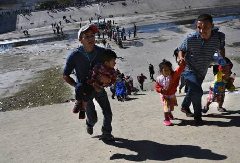 November 25, 2018 - Tijuana, Mexico - Crossing the almost dry Tijuana river. Migrant caravan from camp Centro Deportivo Benito Juarez marches to the Tijuana-San Diego border on November 25, 2018. They were met by a line of Mexican police in riot gear at the bridge but managed to run past them, climbing up steep walls, crossing the Rio Tijuana and difficult terrain, reaching the border but were met at times by tear gas from U.S. agents when they tried to climb over fence and were pleading to be let in. Eventually Mexican police moved the crowd, including many women and children back to the shelter. Tijuana Mexico - ZUMAg208 20181125_zap_g208_023 Copyright: xCarolxGuzyx