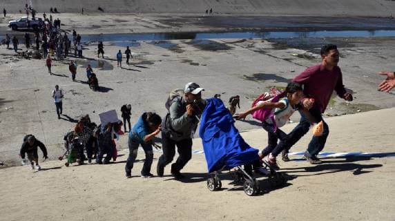 November 25, 2018 - Tijuana, Mexico - Crossing the almost dry Tijuana river. Migrant caravan from camp Centro Deportivo Benito Juarez marches to the Tijuana-San Diego border on November 25, 2018. They were met by a line of Mexican police in riot gear at the bridge but managed to run past them, climbing up steep walls, crossing the Rio Tijuana and difficult terrain, reaching the border but were met at times by tear gas from U.S. agents when they tried to climb over fence and were pleading to be let in. Eventually Mexican police moved the crowd, including many women and children back to the shelter. Tijuana Mexico - ZUMAg208 20181125_zap_g208_027 Copyright: xCarolxGuzyx
